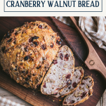 Sliced loaf of cranberry walnut no knead bread with text title box at top