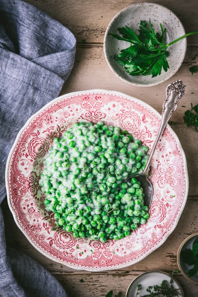 Overhead shot of old fashioned creamed peas in a vintage red and white bowl
