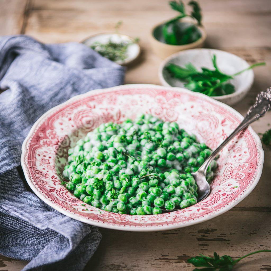 Square side shot of a bowl of creamed peas on a table
