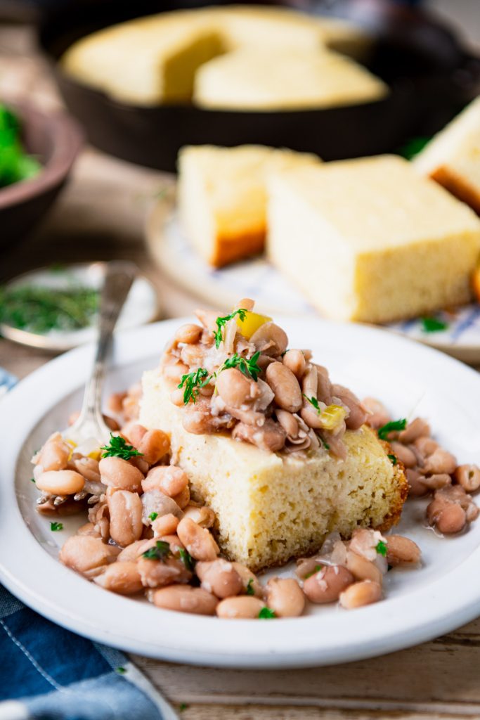 Close up side shot of a plate of crock pot beans and cornbread