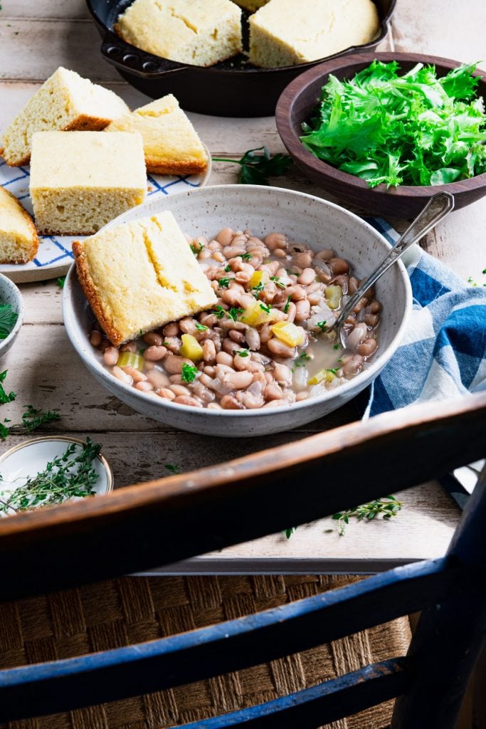 Chair in front of a table with a bowl of slow cooker beans and cornbread