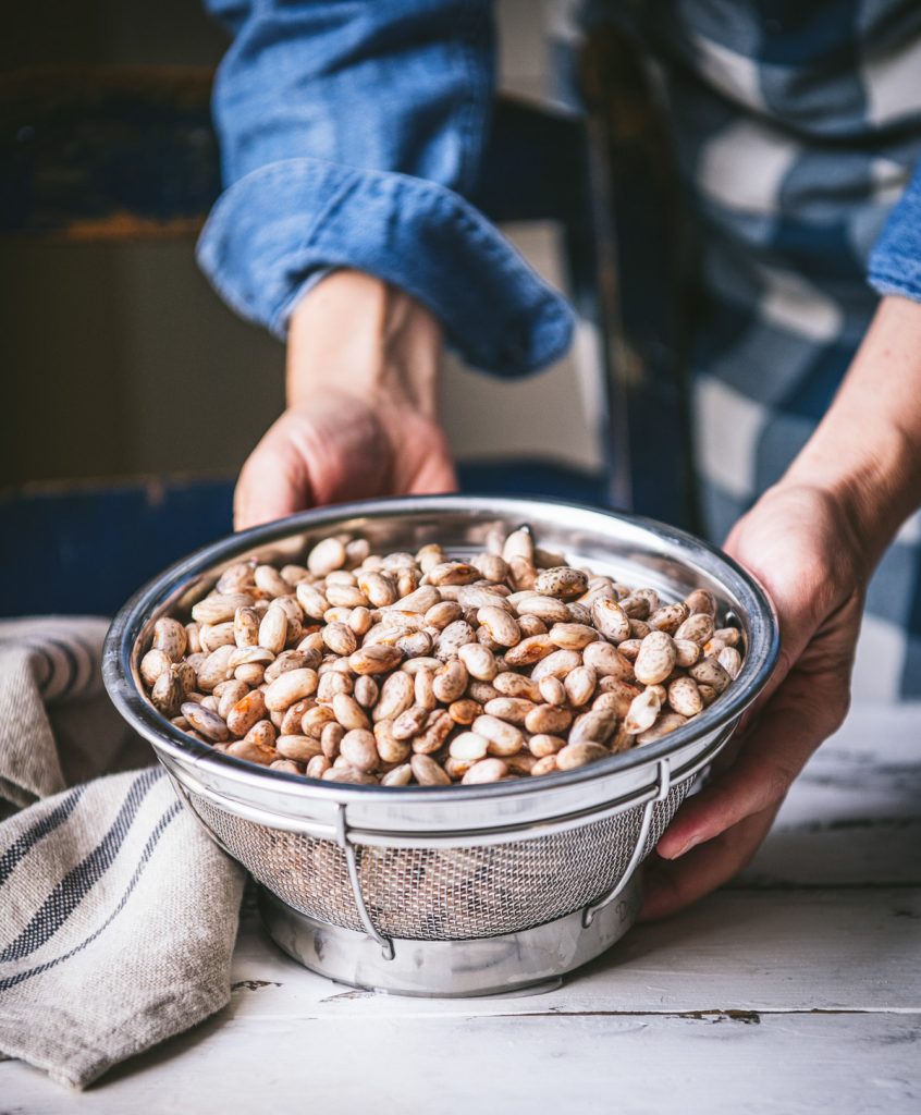 Draining soaked pinto beans in a colander