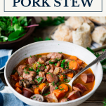 Side shot of a bowl of pork stew with text title box at top