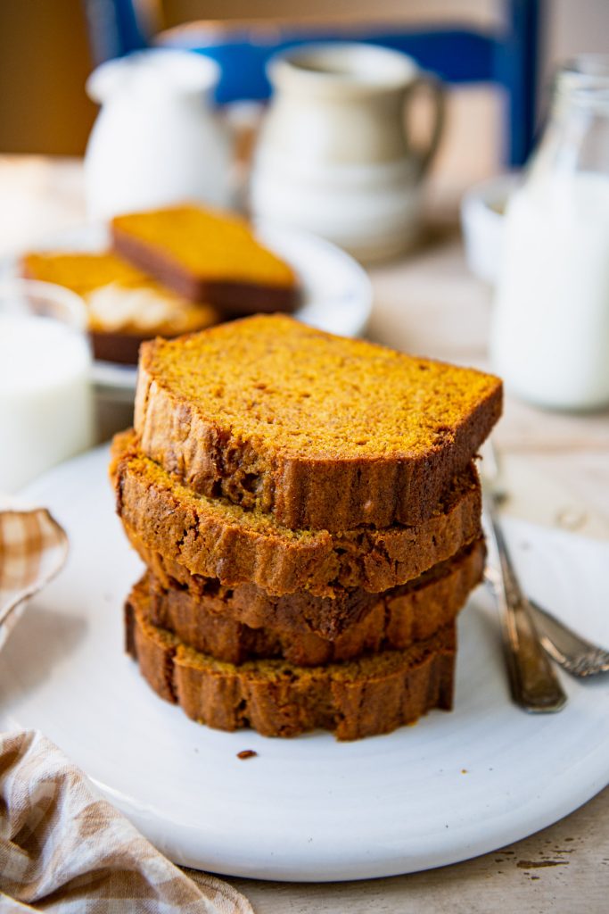 Close up side shot of stacked slices of one bowl pumpkin bread on a white tray