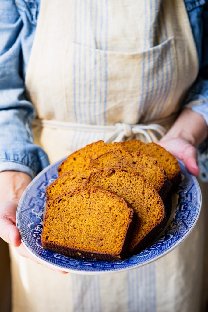 Hands holding a blue and white tray of pumpkin bread