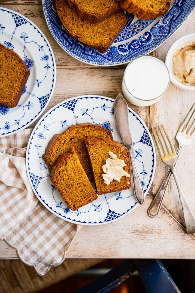 Overhead shot of plates of pumpkin bread on a breakfast table with coffee and milk