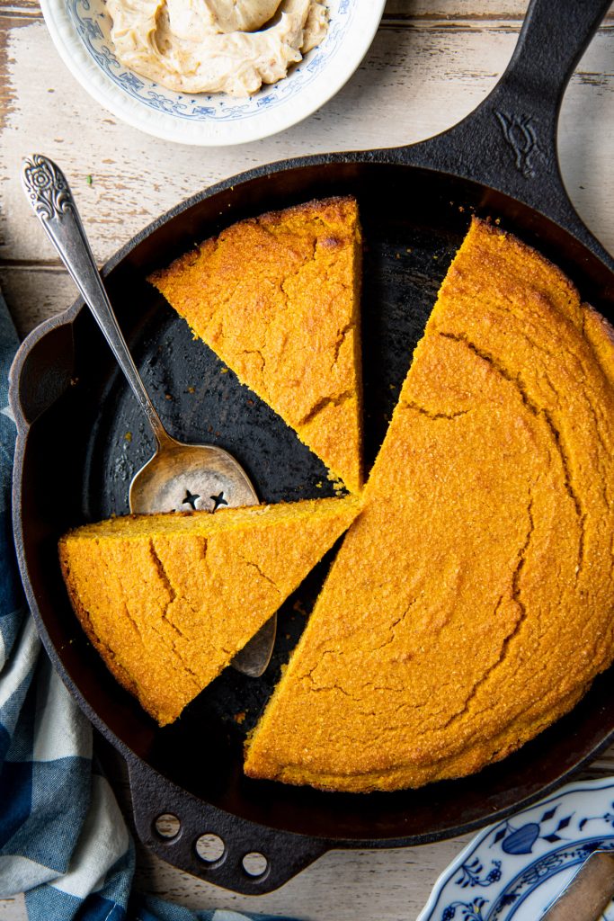 Close overhead image of a sliced wedges of pumpkin cornbread in a skillet