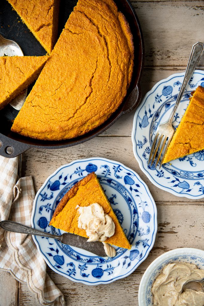 Slices of pumpkin cornbread on blue and white plates on a wooden table