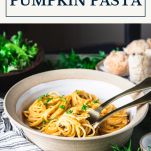Side shot of a bowl of creamy pumpkin pasta with text title box at top