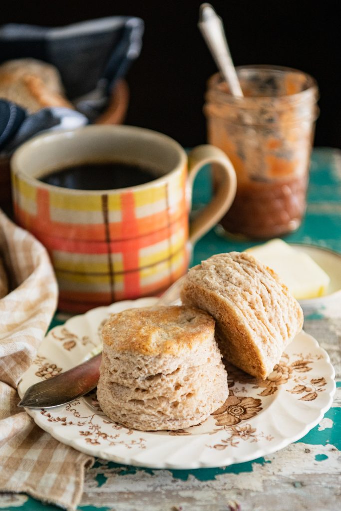 Side shot of a small plate of pumpkin spice biscuits on a table with a mug of coffee