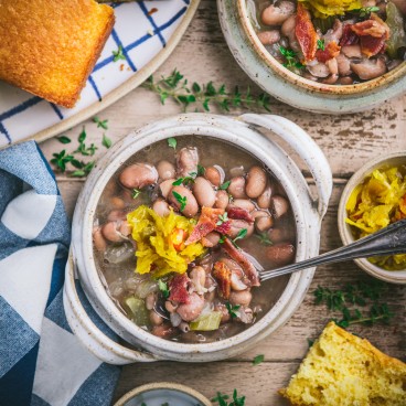 Square overhead image of a bowl of appalachian soup beans on a wooden table with a side of cornbread
