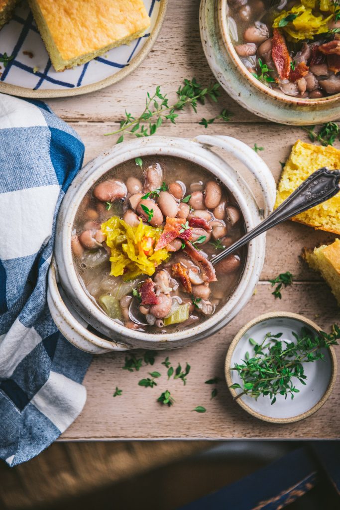 Bowls of soup beans on a wooden table with a side of cornbread