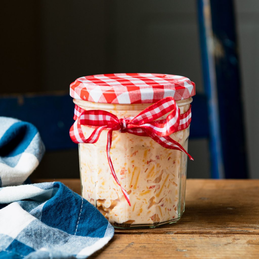 Jar of easy pimento cheese spread in a jar with a red and white lid