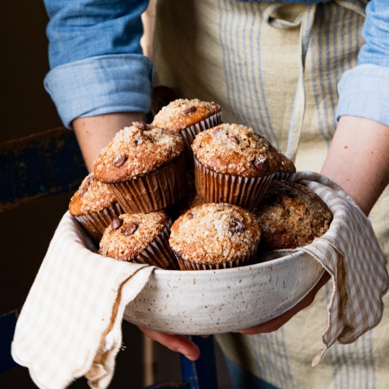 Hands holding a bowl of banana chocolate chip muffins