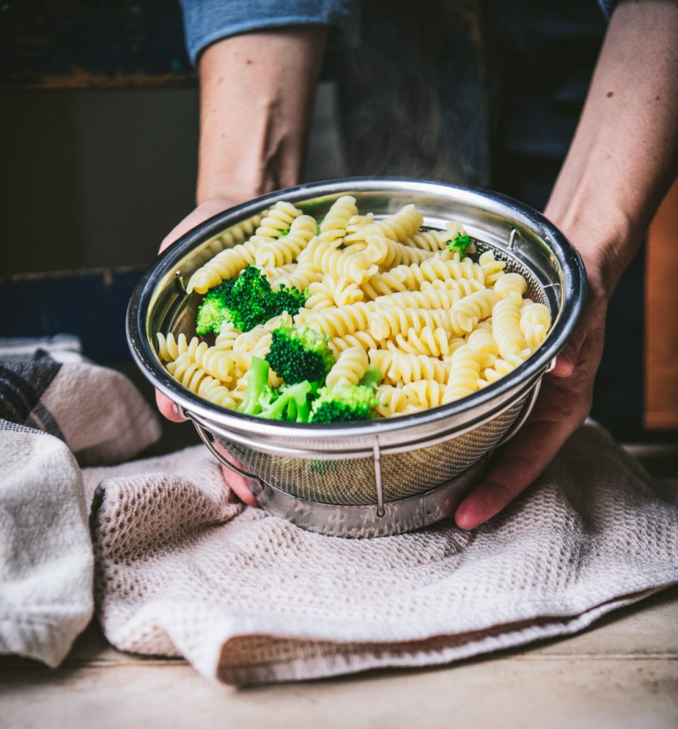 Boiled pasta and broccoli in a colander