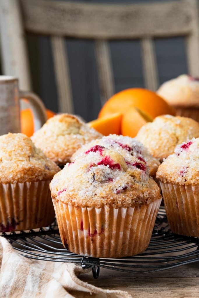 Side shot of cranberry orange muffins on a cooling rack