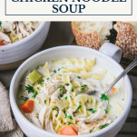 Side shot of a bowl of creamy chicken noodle soup with text title box at top