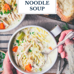 Overhead shot of hands eating a bowl of creamy chicken noodle soup with text title overlay