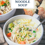 Close up side shot of a bowl of creamy chicken noodle soup with text title overlay