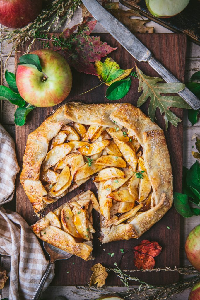 Overhead image of a sliced apple galette on a wooden cutting board