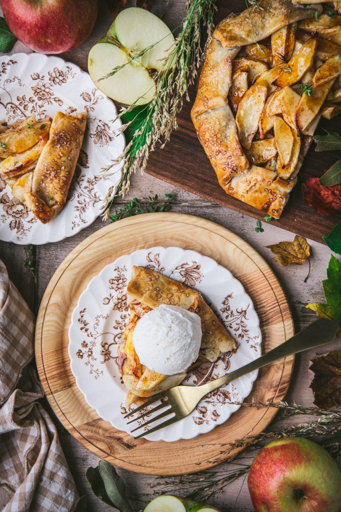 Overhead shot of slices of apple galette on plates on a table with vanilla ice cream