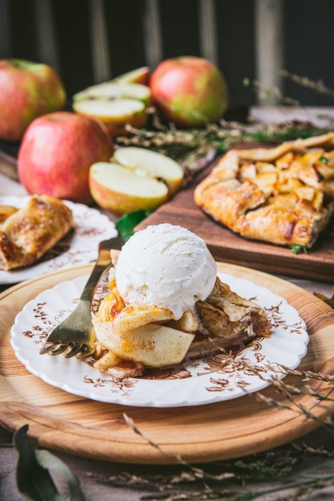 Front shot of a slice of apple galette with a scoop of vanilla ice cream on top