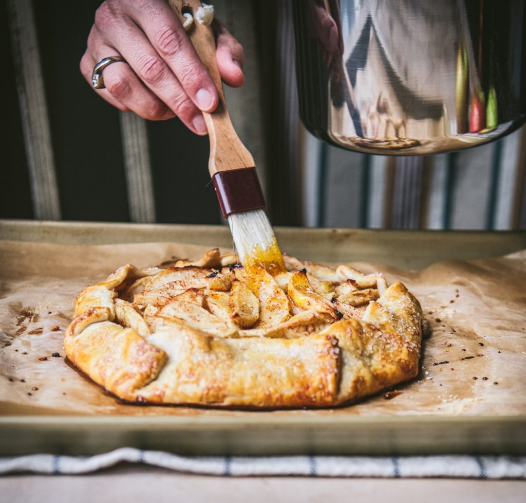 Brushing apricot jam on an apple galette
