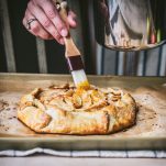 Brushing apricot jam on an apple galette
