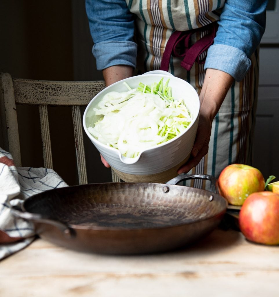 Adding cabbage and onion to a skillet