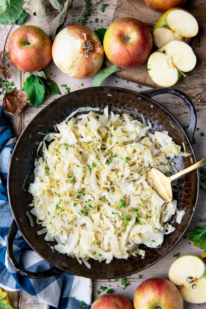 Overhead shot of a pan of fried cabbage with onions and apples in a skillet