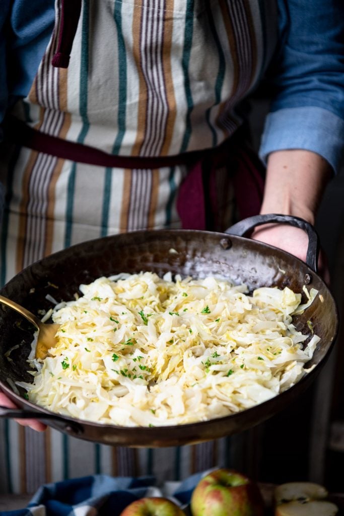 Hands holding a pan of vegetarian fried cabbage