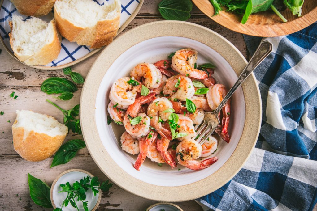 Overhead shot of a bowl of garlic shrimp with a side of crusty bread