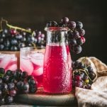 Square image of a pitcher of homemade grape juice