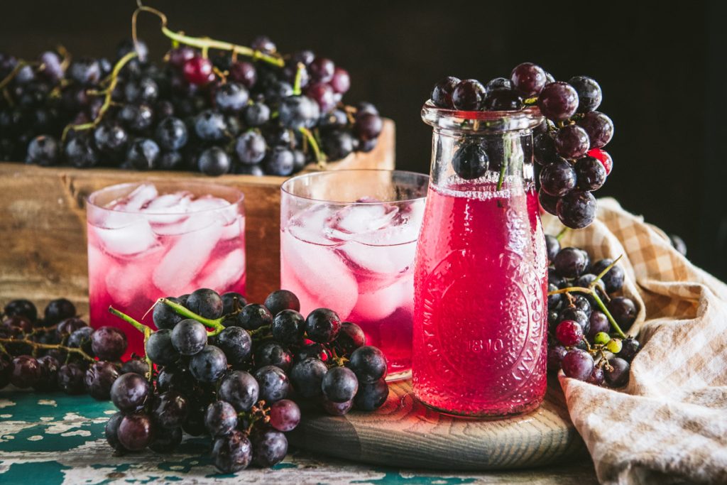 Horizontal shot of homemade grape juice and grapes on a table