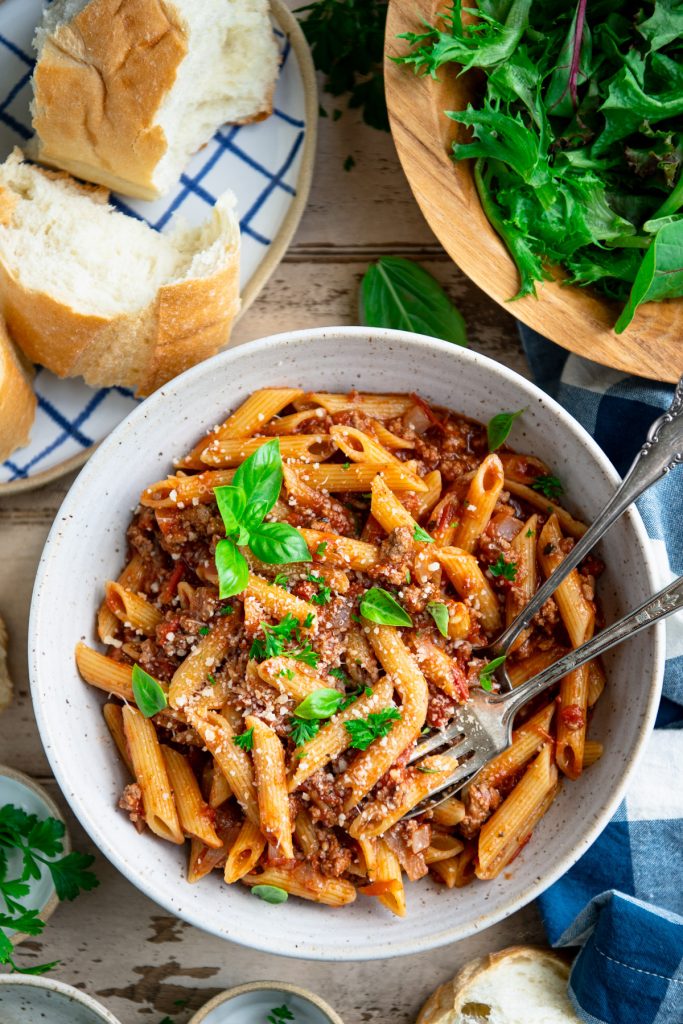 Close overhead image of a bowl of one pot pasta with ground beef on a dinner table