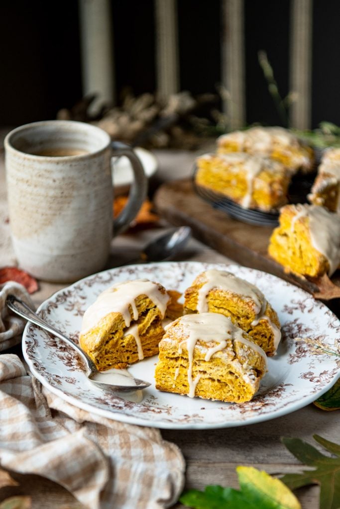 Side shot of fall leaves on a table with a plate of pumpkin scones