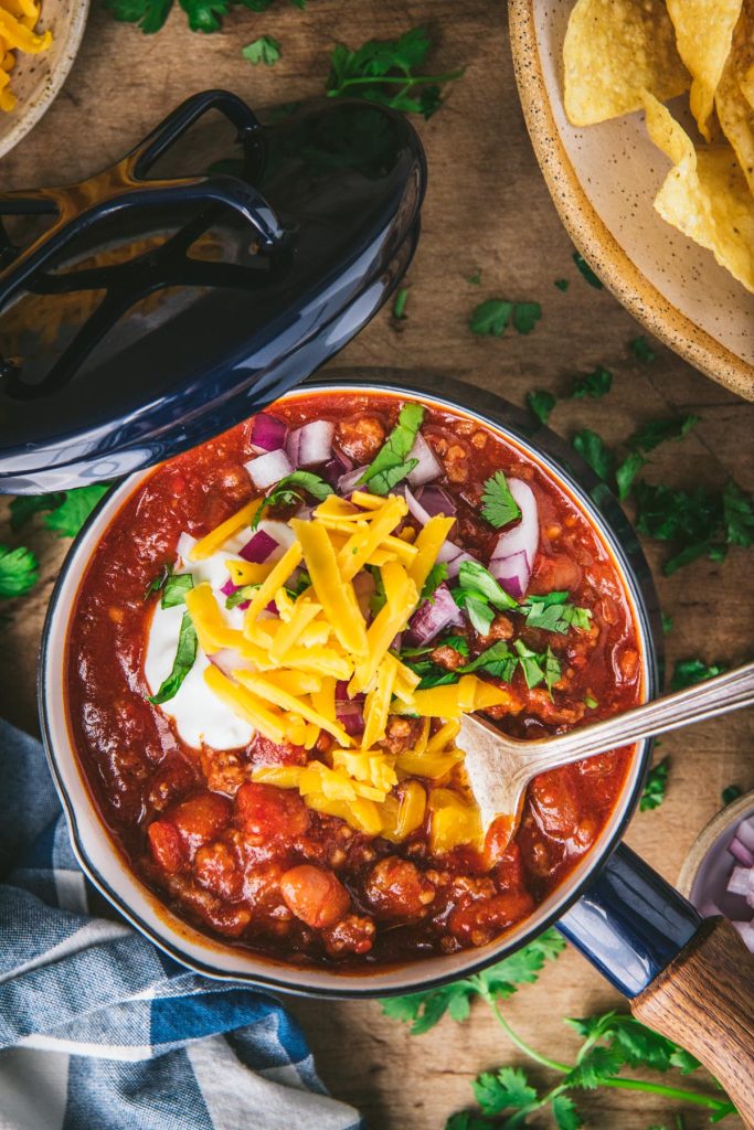 Overhead image of a pot of a bowl of taco chili with cheese and other toppings