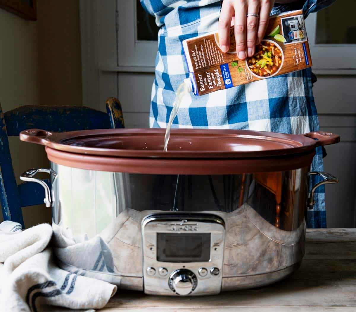 Pouring chicken broth into a slow cooker.