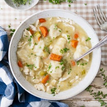 Square overhead shot of crock pot chicken and dumplings in a white bowl.
