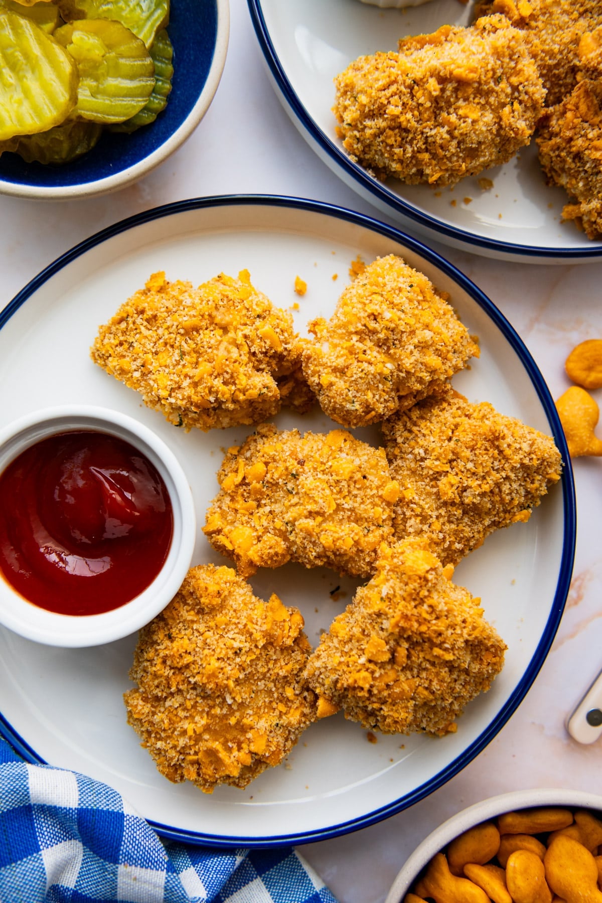 Close overhead shot of crispy baked chicken nuggets on a blue and white plate with ketchup for dipping.