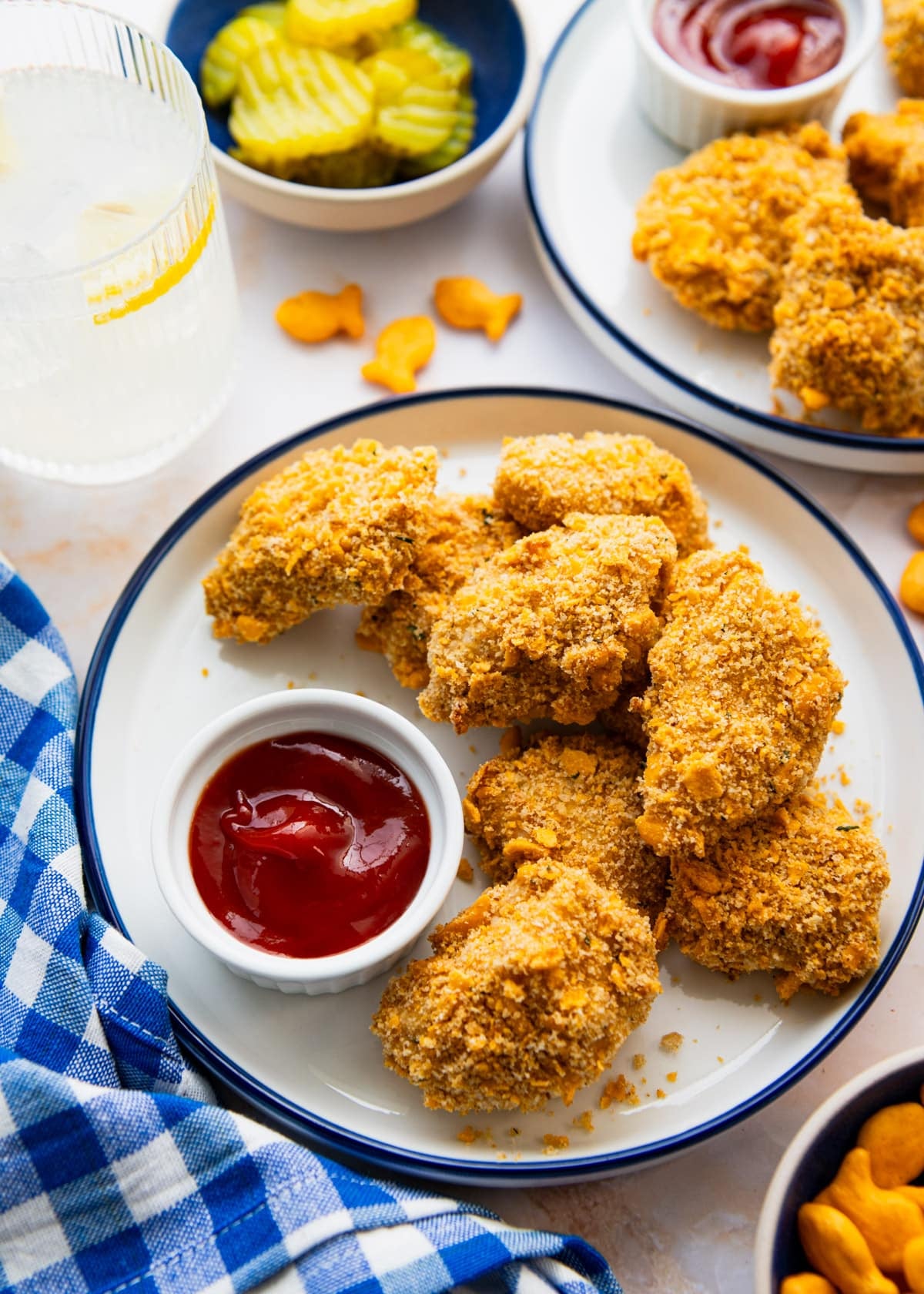 Side shot of crispy baked chicken nuggets on a blue and white plate with ketchup for dipping.