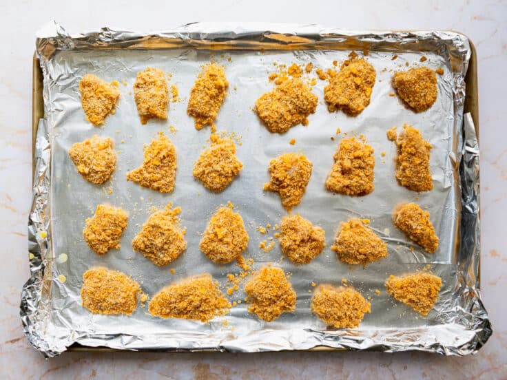 Chicken nuggets on a baking sheet before they go in the oven.