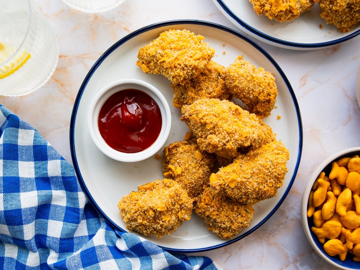 Horizontal overhead shot of crispy baked chicken nuggets on a blue and white plate with ketchup for dipping.