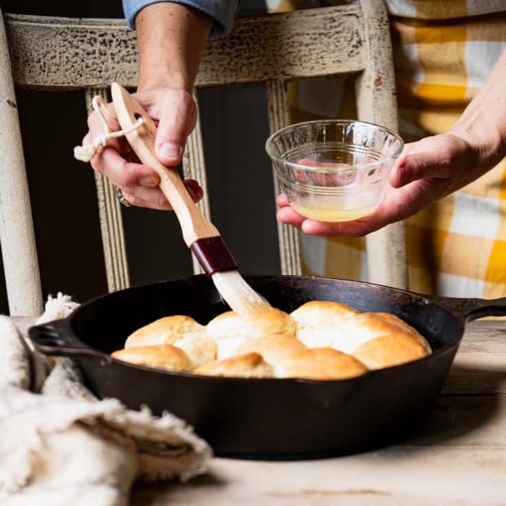 Brushing melted butter on bisquick 7up biscuits.