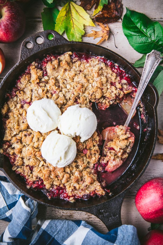 Overhead shot of apple cranberry crisp in a cast iron skillet with ice cream on top