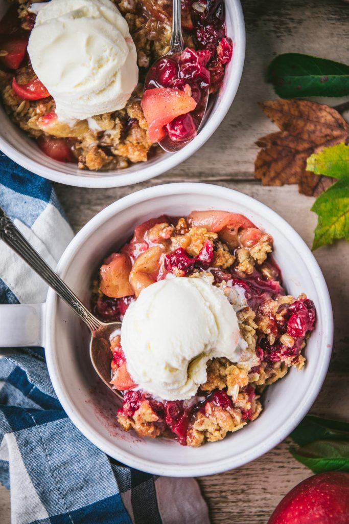 Close overhead shot of a bowl of apple cranberry crisp with a scoop of ice cream on top