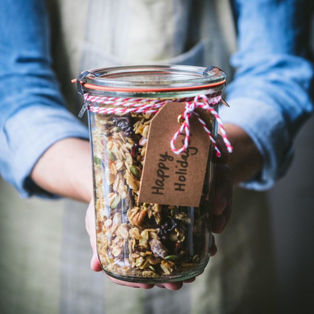Square image of hands holding a jar of homemade granola