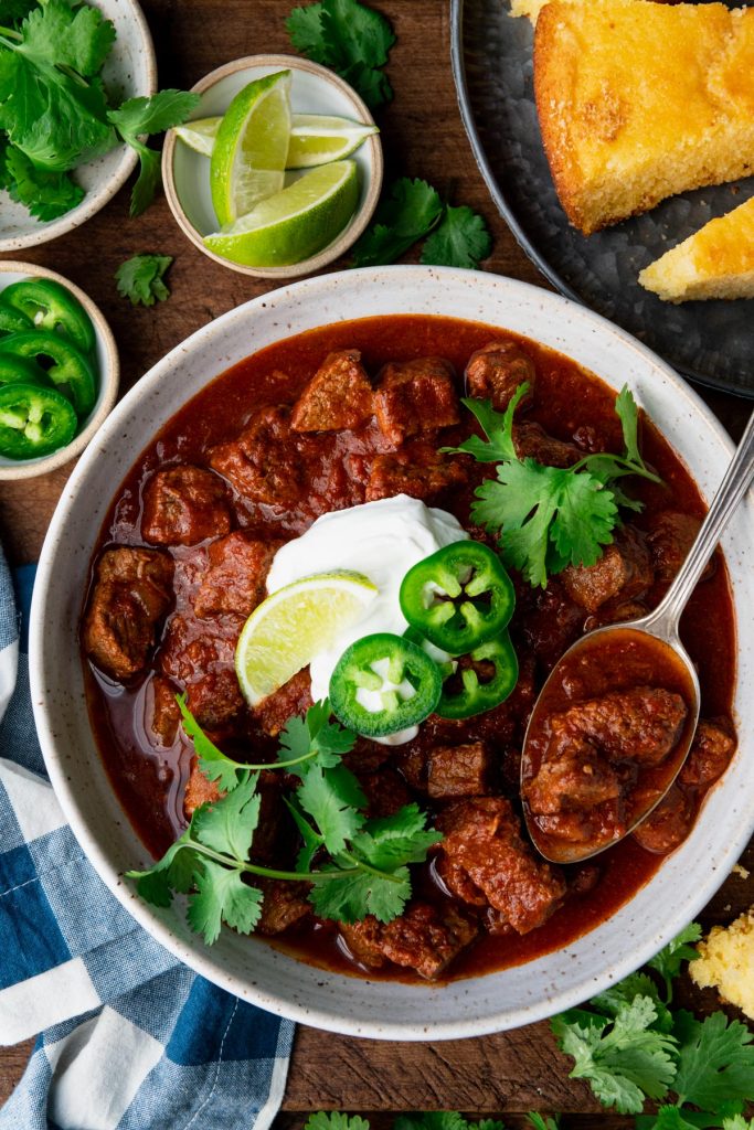 Close overhead image of a bowl of texas style chili with a side of cornbread