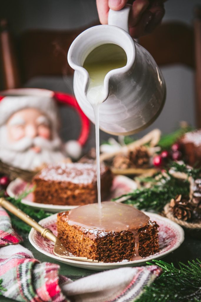 Front shot of pouring lemon sauce over a slice of traditional gingerbread cake