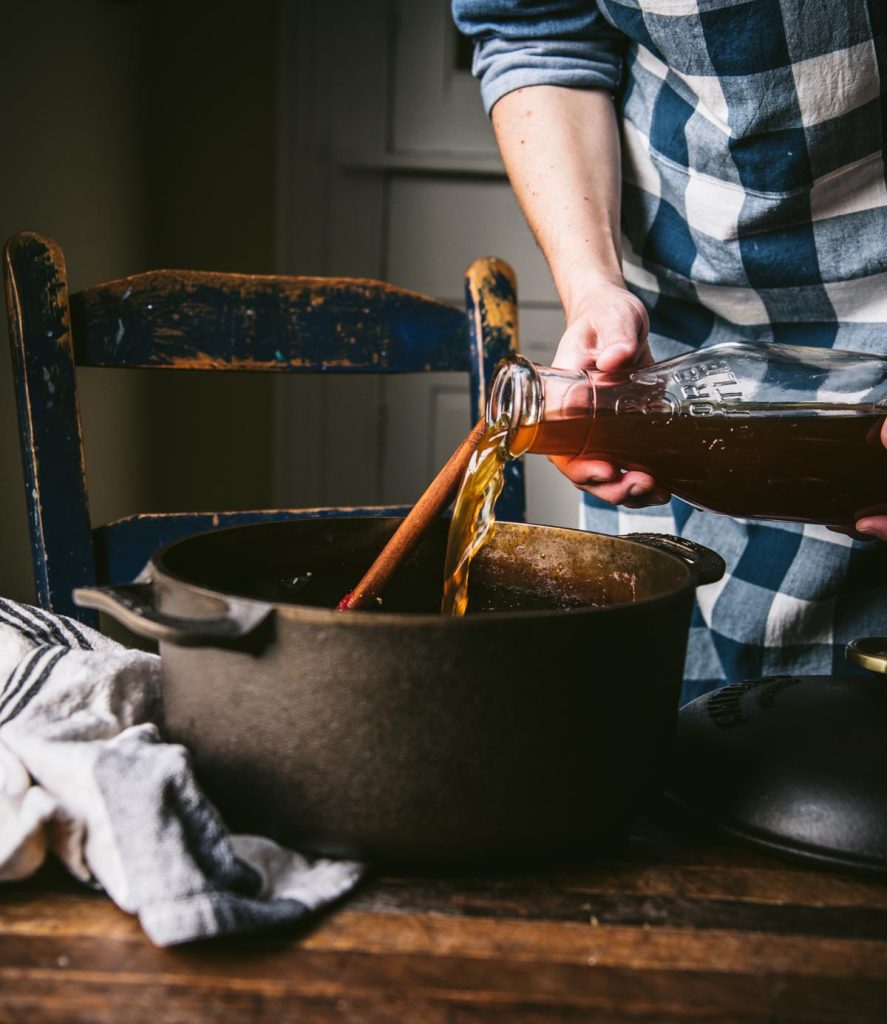 Pouring beef broth into a Dutch oven